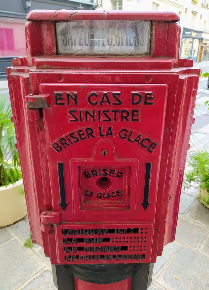 Close-up of fire alarm call box: “En cas de sinistre, briser la glace.”