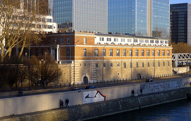 Brick building standing by a river, with modern glass towers in background