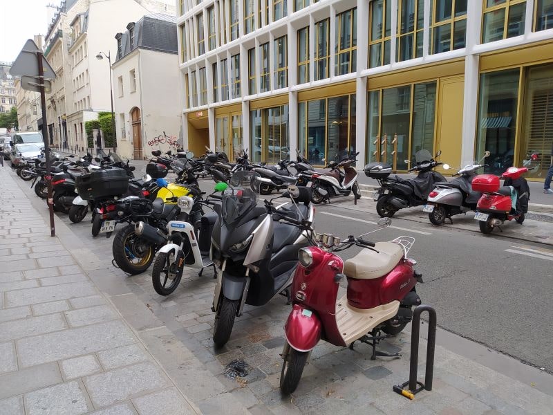 Rows of parked motorcycles either side of a narrow one-way street