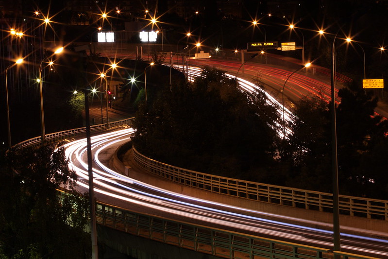 Long-exposure photograph, taken at night, two wide areas of white lights and one of red