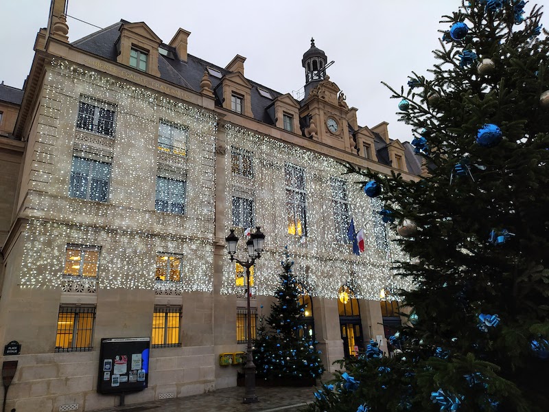 Christmas trees and lights in front of a town hall building